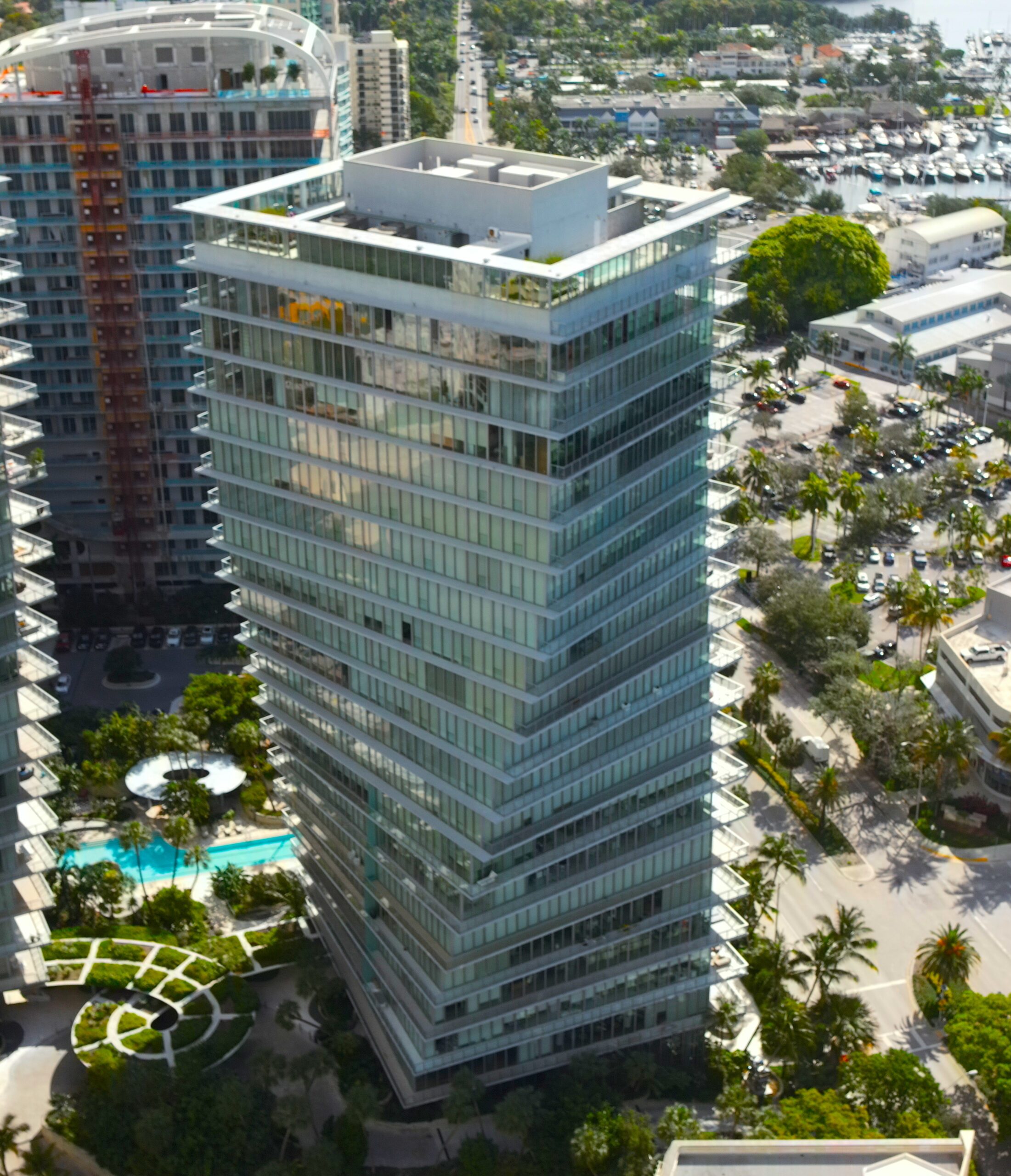 Aerial drone view of a high-rise condominium tower and pool deck in Florida