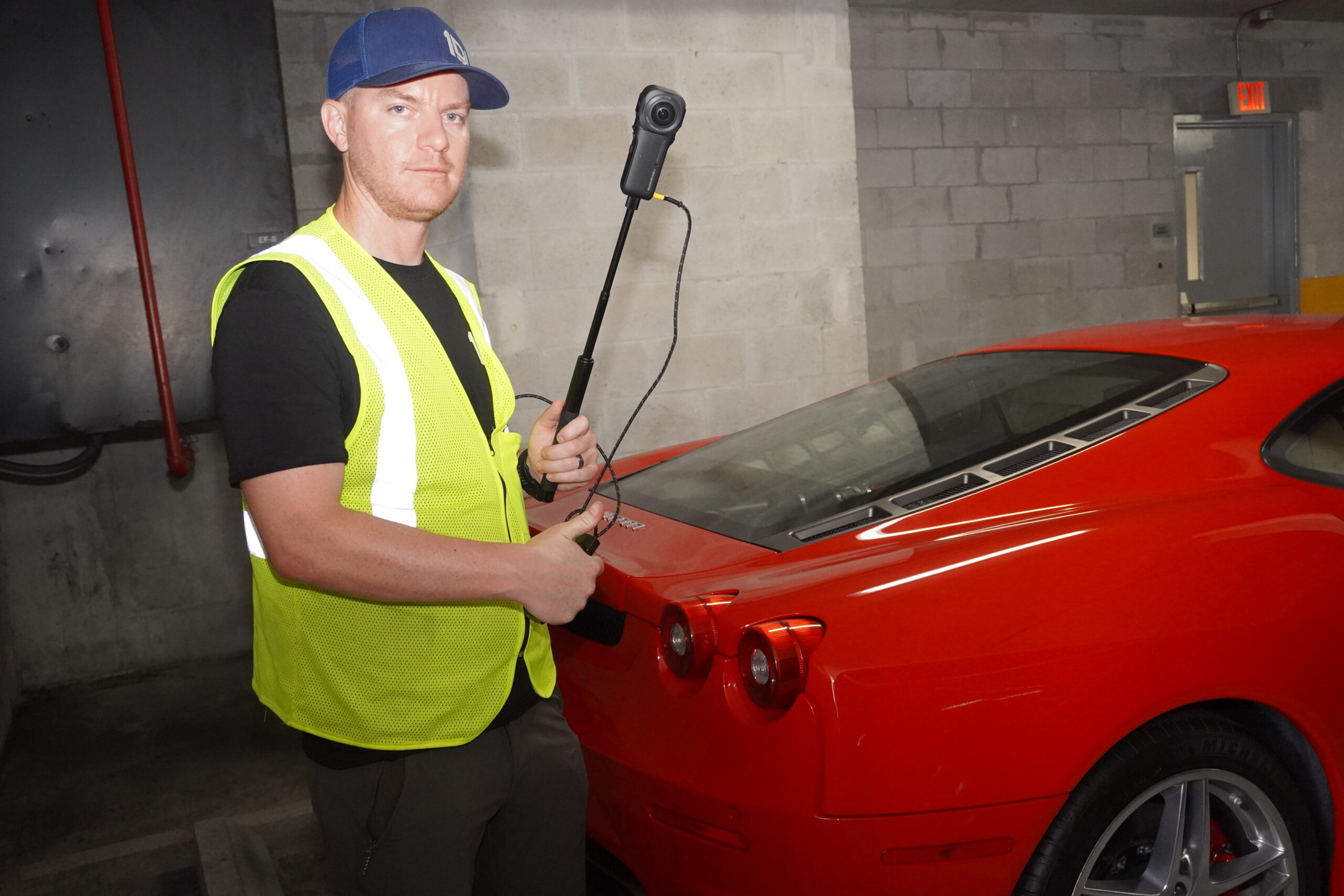 Technician using a handheld 3-D scanner beside a sports car in a parking garage
