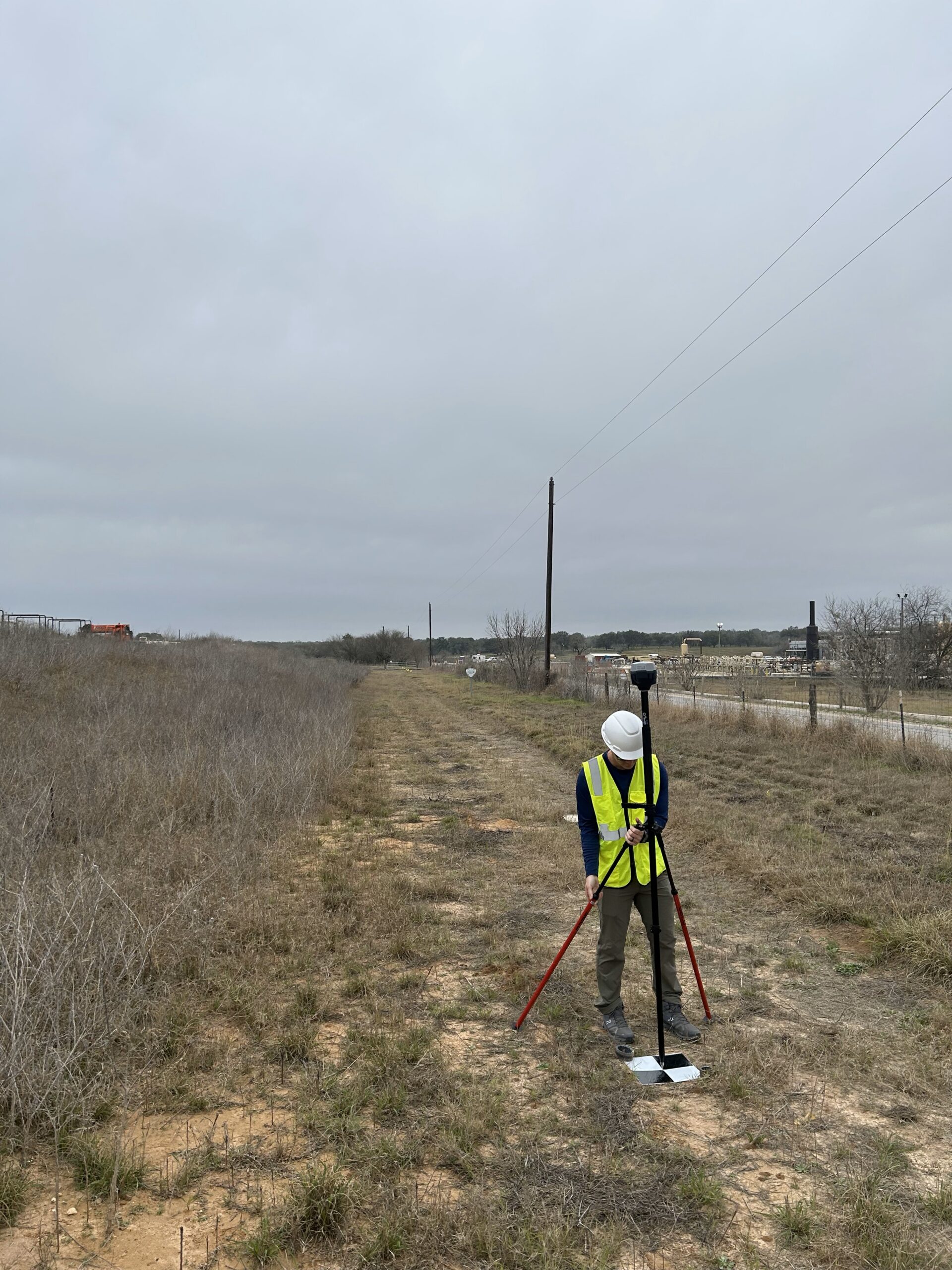 Surveyor holding a GNSS rover pole to collect ground control points in a field